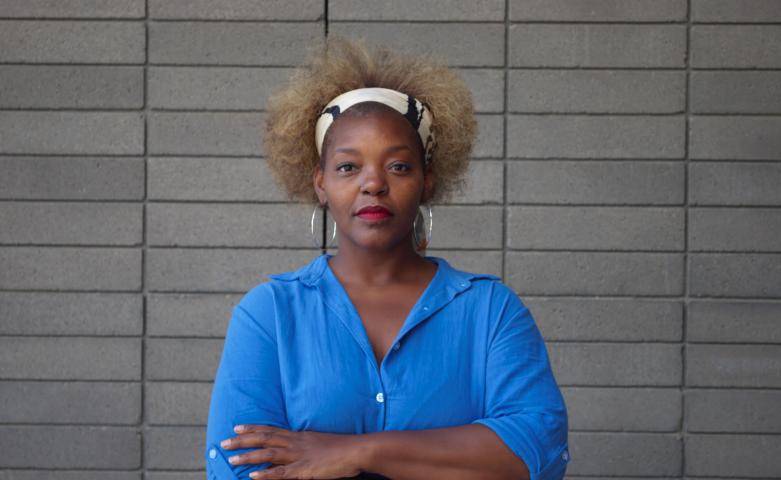 Mahogany L. Browne with her arms folded wearing a blue shirt